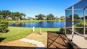 A lakeside view with a modern building featuring large windows. - Tranquil lakefront pool home in North Port - Rod And Reel (North Port)