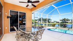 A glass-enclosed patio with a pool, outdoor furniture, and a view of a golf course. - Tranquil lakefront pool home in North Port - Rod And Reel (North Port)