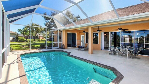 A covered swimming pool area with a patio and outdoor seating. - Tranquil lakefront pool home in North Port - Rod And Reel (North Port)