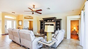 A spacious living room with a large sofa, a coffee table, and a fireplace. - Tranquil lakefront pool home in North Port - Rod And Reel (North Port)