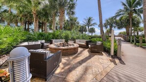 Un patio al aire libre con un brasero, muebles de mimbre y palmeras.