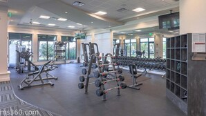 Un gimnasio con equipo de levantamiento de pesas, máquinas de cardio y mancuernas.