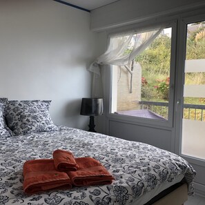 Ein Schlafzimmer mit einem Bett, einem Fenster mit Blick auf Grünflächen und einer Lampe.
