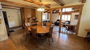 A spacious dining area with a wooden table and chairs, a ceiling fan, and a view into the living room. - Peaceful, spacious 4 bedroom house in the country - Gazebo/Pond
 (Keosauqua)