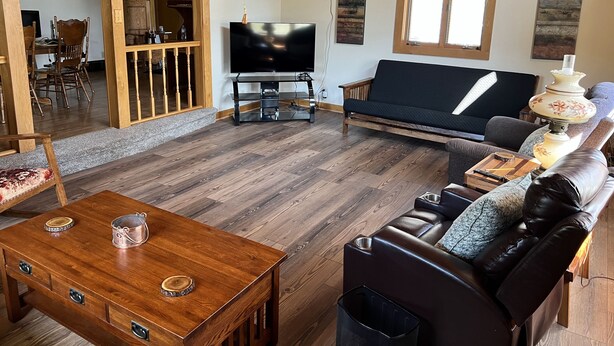 A spacious living room with a wooden floor, a sofa, a coffee table, and a television. - Peaceful, spacious 4 bedroom house in the country - Gazebo/Pond
 (Keosauqua)