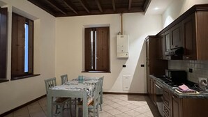 A kitchen with wooden cabinets, a tiled floor, and a dining table with chairs.