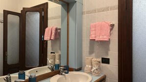 A bathroom with two sinks, a mirror, and towels hanging on the wall.