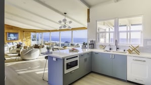 A modern kitchen with a large island, built-in oven, and a view of the ocean. - Sunrise to Sunset Views • Cayucos Beachfront Home (Cayucos)