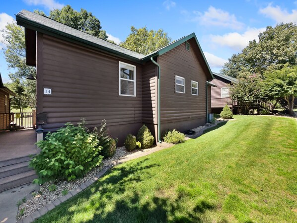 A single-story log cabin with a number '34' sign, a front porch, and a well-maintained lawn.
