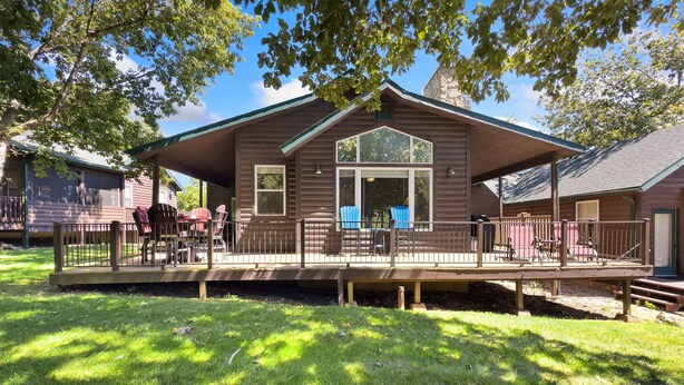 A cabin with a deck, large windows, and a covered porch area.