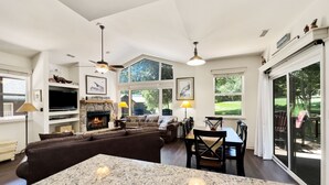 A spacious living room with a fireplace, a large window, and a dining area.