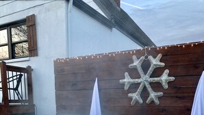 Un bain à remous entouré d’une clôture en bois, avec un flocon de neige décoratif en arrière-plan.
