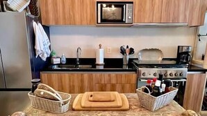 Une cuisine avec des meubles en bois, un four à micro-ondes, une cuisinière et une table décorative agrémentée de paniers et d'une planche à découper.