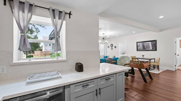 A modern kitchen with grey cabinets, a dishwasher, and a window with curtains. - Med Center 2BR | Gated, Near NRG, MD Anderson (Houston)
