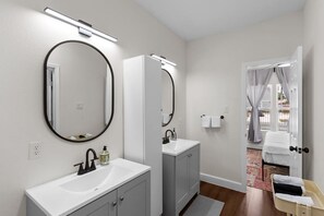 A modern bathroom with two sinks, large mirrors, and a walk-in shower. - Med Center 5BR Duplex | Gated, Near NRG, TMC (Houston)