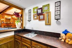 A kitchen with wooden cabinets, a granite countertop, a sink, and decorative mirrors on the wall. - Charming Texas Escape, Near Cedar Hill State Park! (Duncanville)