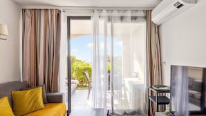 A modern living room with a sofa, a TV, and a sliding glass door leading to an outdoor area. - Appartement Wemyssia - Welkeys (Cannes)
