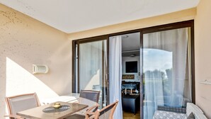 A balcony with a dining table and chairs, a sofa, and a sliding glass door leading to an interior space with a dining table and chairs. - Appartement Wemyssia - Welkeys (Cannes)