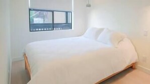 Een slaapkamer met een enkel bed, een raam en een effen muur.