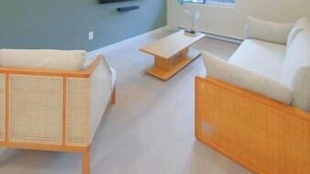 Een moderne woonkamer met een bank, salontafel en een televisie aan de muur.