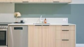Een moderne keuken met lichte houten kastjes, een roestvrijstalen oven en een wit aanrecht.