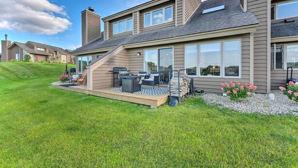 Une maison moderne à deux étages, dotée d’une terrasse, d’un espace salon extérieur et d’une grande fenêtre donnant sur la cour.