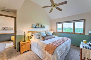A bedroom with a bed, a nightstand, a desk, a ceiling fan, a window, and a view of the outdoors. - Boutique townhome w/ fire pit, KING bed, mezzanine loft & golf views! (Galena)