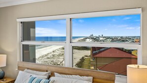 A hotel room with a large window offering a view of the beach and cityscape.