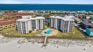 A beachfront hotel with multiple high-rise buildings, a central pool, and a beach in the foreground.