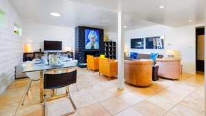 A modern living room with a glass dining table, a fireplace, and a TV mounted on the wall. - Perfect 4 Families, Amazing Reviews Pool & Jacuzzi (Palm Springs)