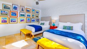 A hotel room with two beds, a ceiling fan, and a wall adorned with framed pictures. - Perfect 4 Families, Amazing Reviews Pool & Jacuzzi (Palm Springs)