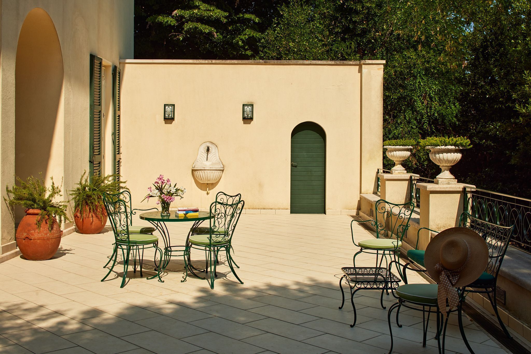 Eine Außenpatio mit Tisch und Stühlen, Blumentöpfen und einer grünen Tür.