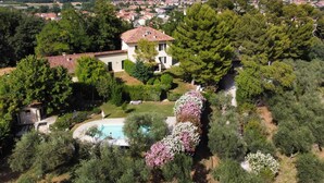 A large house with a swimming pool surrounded by lush greenery and flowering plants. - Villa Monacelli (Fano)