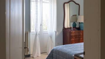 A bedroom with a bed, a dresser, a mirror, and a window with curtains.