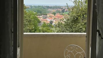 Varanda com vista para uma cidade, uma cadeira de metal e piso de azulejos.