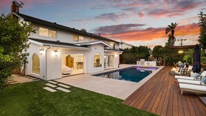 Uma casa moderna com piscina, deck e gramado bem cuidado.