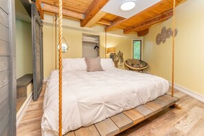 Camera da letto con un letto su una piattaforma in legno, soffitto in legno e vista sull'esterno.