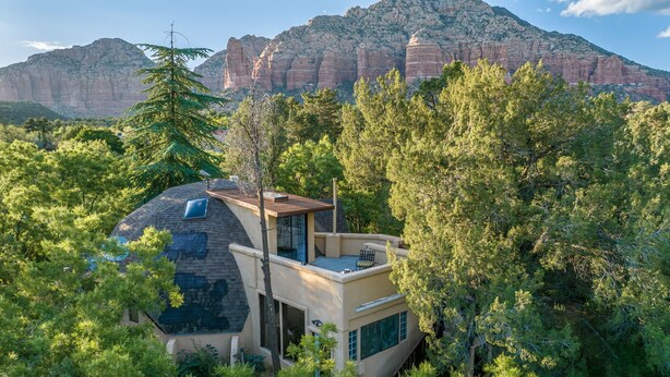 A modern house with a sloped roof, large windows, and a view of red rock formations. - Beautiful Unique home with yoga/meditation studio! (Sedona)