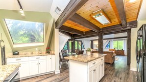 A spacious kitchen with a large island, wooden beams, and a view of the outdoors. - Beautiful Unique home with yoga/meditation studio! (Sedona)