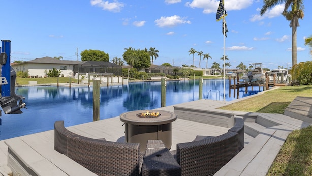 A poolside area with a fire pit, outdoor furniture, and a flag. - Pet friendly sailboat access property w/4BRs! Great for families! Villa Andrea - SWFL Rentals (Cape Coral)