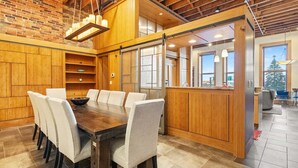 A modern kitchen with wooden cabinetry, a dining table with chairs, and a view of the outdoors.