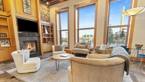 A spacious living room with a fireplace, large windows, and a cozy seating area.