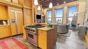 A modern kitchen with wooden cabinets, a built-in stove, and a large island.