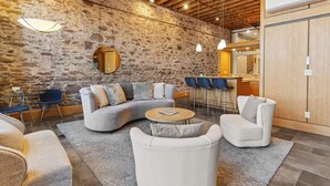 A modern lounge area with a stone wall, a curved sofa, and a round coffee table.