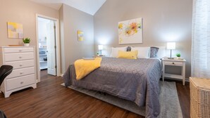 A bedroom with a bed, bedside tables, a dresser, and a ceiling fan.