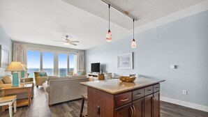 A modern living room with a wooden cabinet, a dining area with a table and chairs, and a kitchen with a countertop and a bowl.