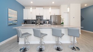 A modern kitchen with white cabinets, stainless steel appliances, and a central island with bar stools. - LN4816 Storey Lake Home 4Beds 3Baths Private Pool and Free Waterpark (Kissimmee)