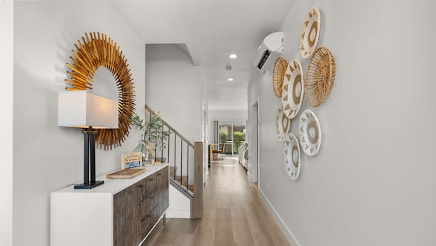 A modern hallway with a wooden floor, a white console table with a lamp, a decorative wall piece, and a staircase. - 12 The Vues | Resort pool, Private balcony, (Saint George)