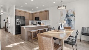 A modern kitchen with a central island, stainless steel appliances, and a dining area with a wooden table and chairs. - 12 The Vues | Resort pool, Private balcony, (Saint George)