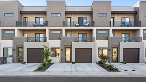A modern multi-story residential building with a symmetrical facade, balconies, and garage doors. - 12 The Vues | Resort pool, Private balcony, (Saint George)
